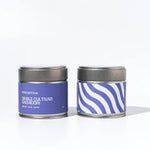 Two tea tins with purple labels on a white background
