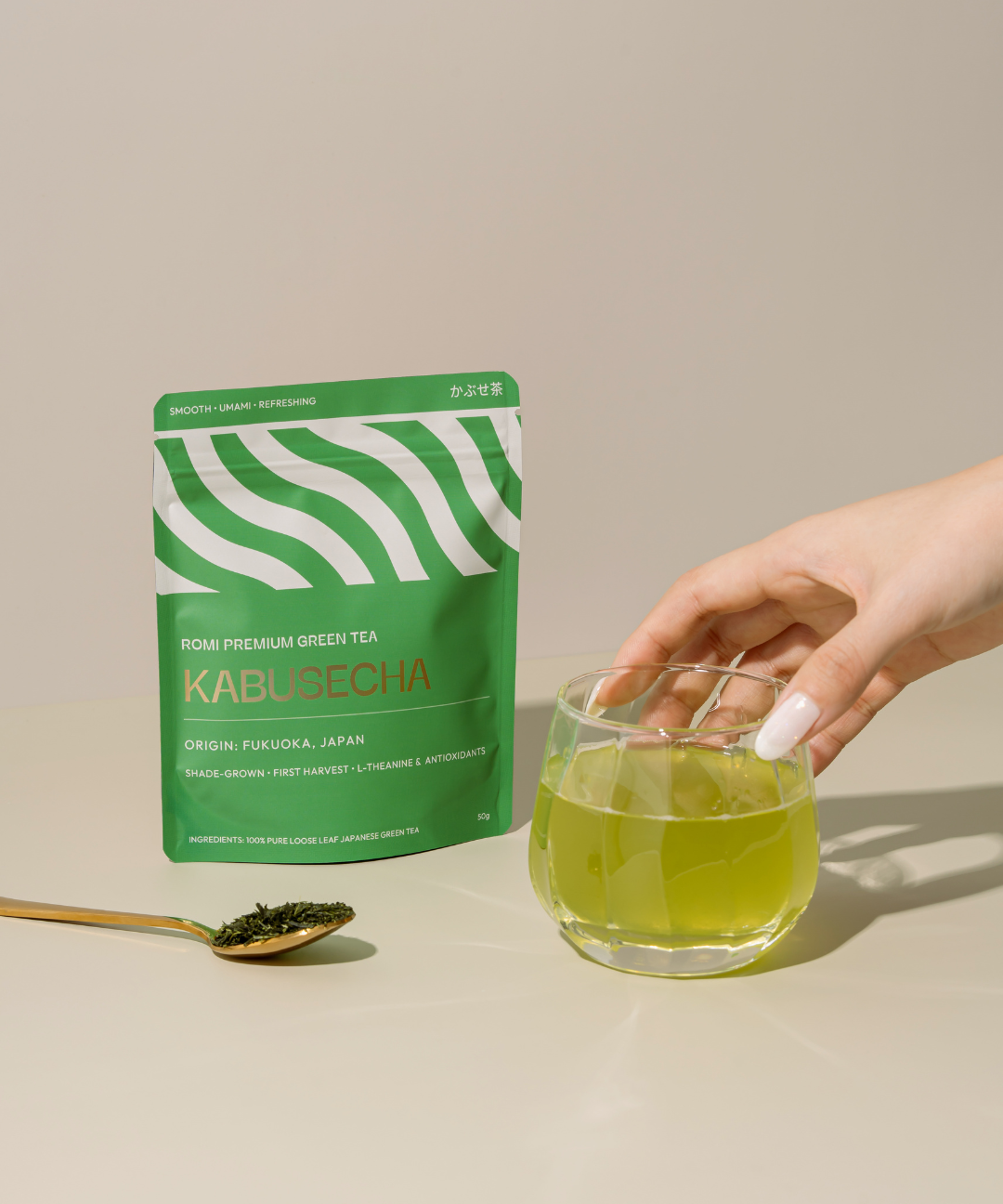 Green tea package and glass of green tea on a beige background