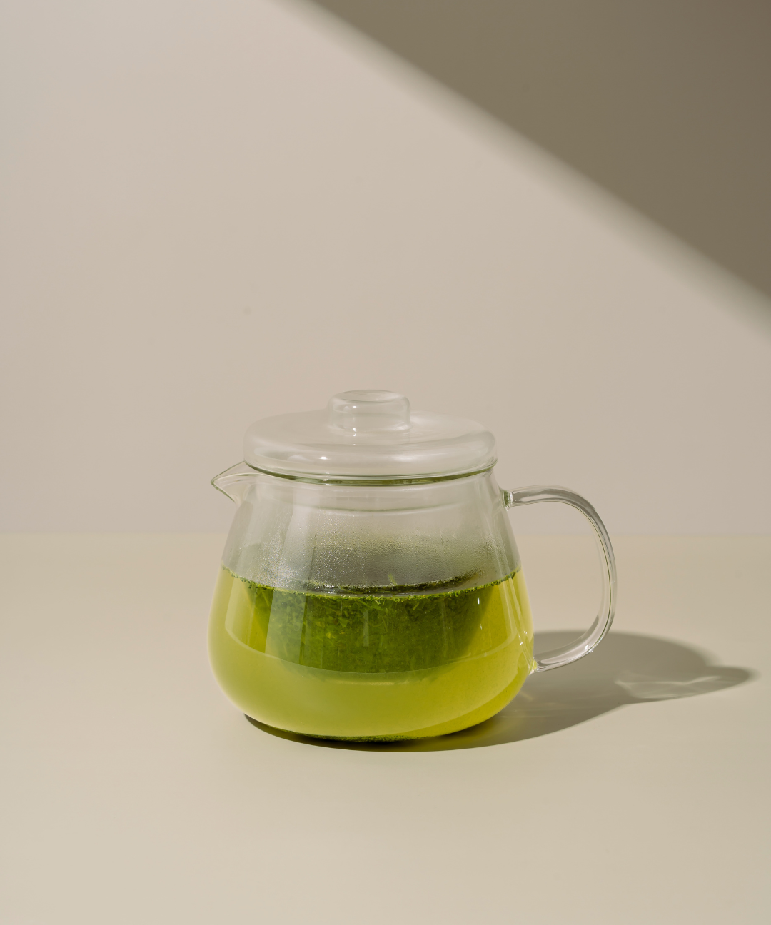 Clear glass teapot with Kabusecha Premium Shaded Green Tea on neutral background | Romi Matcha