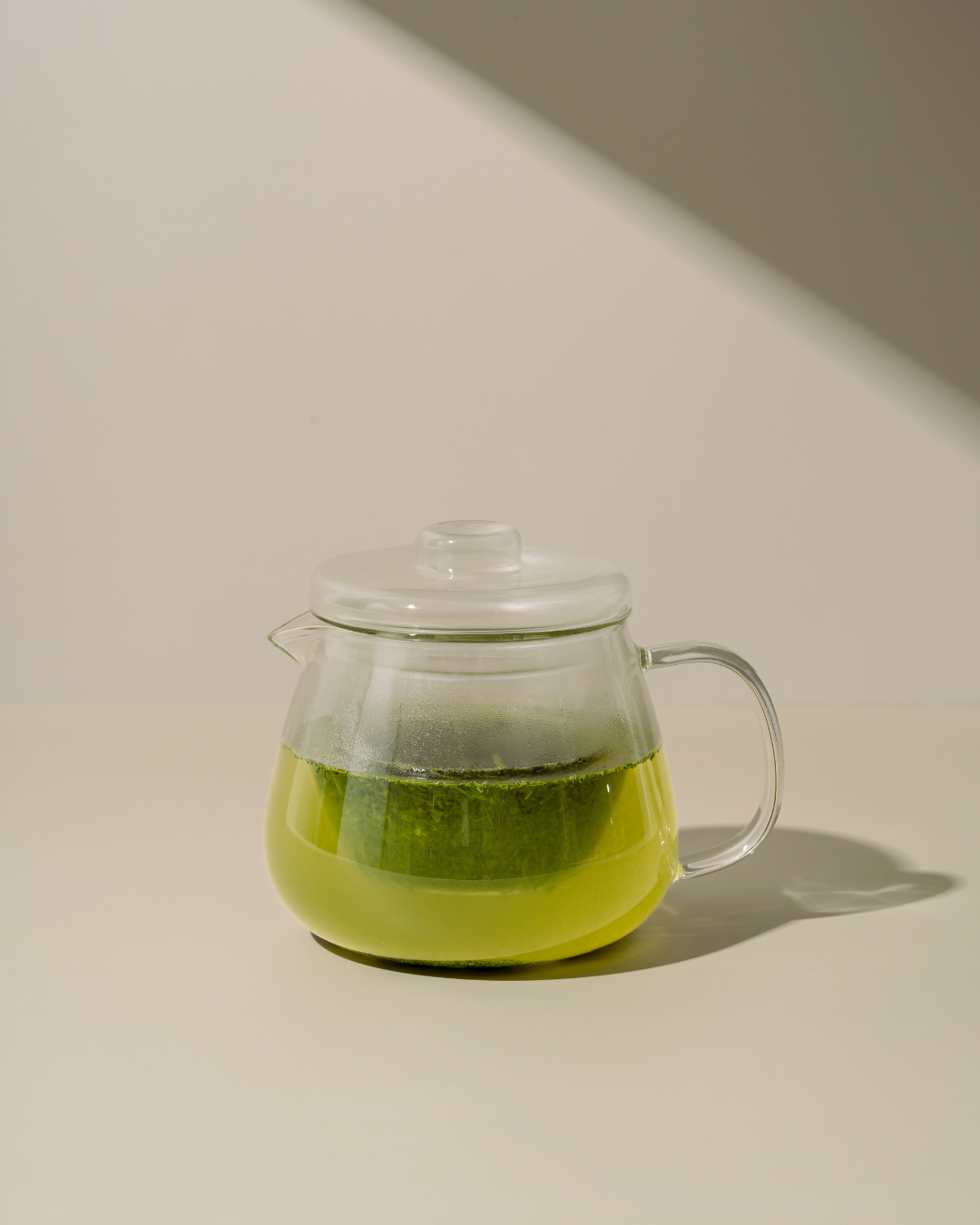 Clear glass teapot with Kabusecha Premium Shaded Green Tea on neutral background | Romi Matcha