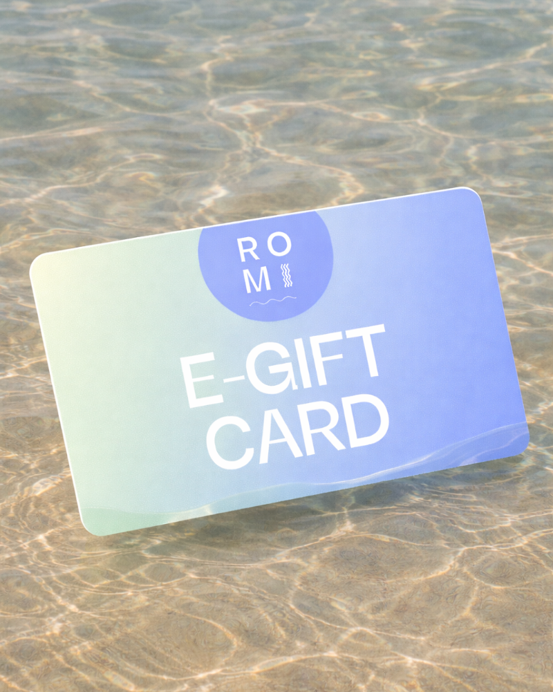 E-gift card with 'ROM' branding on a sandy surface
