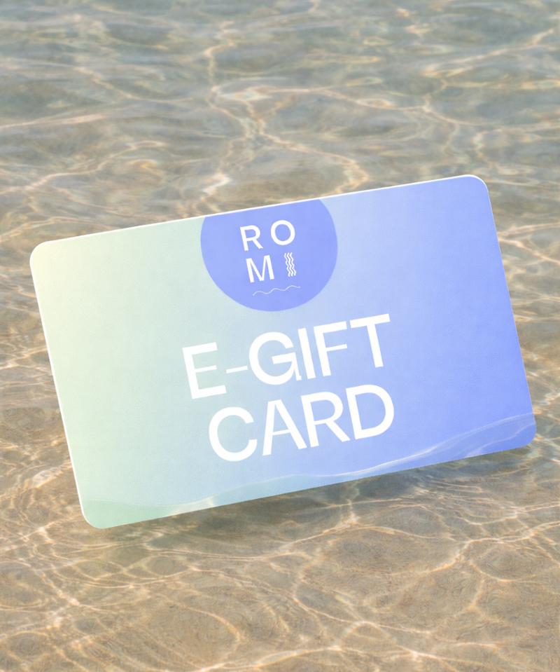 E-gift card with 'ROM' branding on a sandy surface