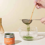 Okumidori Matcha tins with hands sifting matcha into a bowl