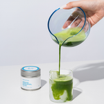 Hand pouring Romi Matcha Organic Ceremonial Blend matcha latte on white background