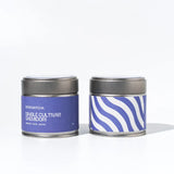 Two tea tins with purple labels on a white background