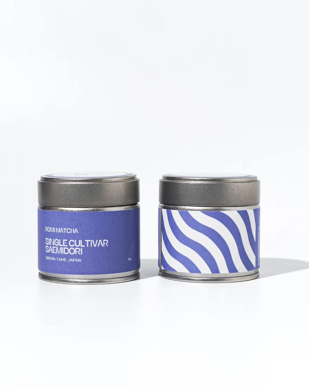 Two tea tins with purple labels on a white background