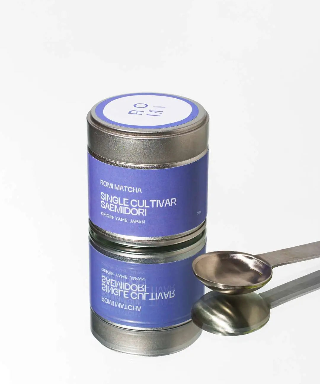 Tea canister with a purple label and silver spoon on a white background