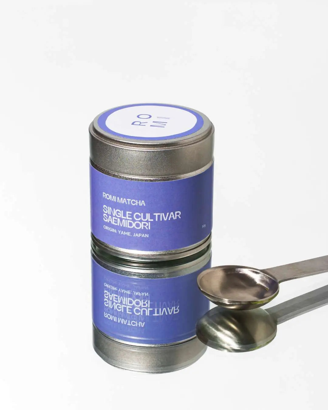 Tea canister with a purple label and silver spoon on a white background
