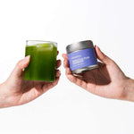 Two hands holding a glass of Romi Matcha Saemidori matcha and 30g tin