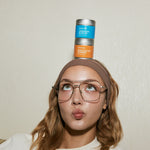 Person balancing matcha tins on their head with a neutral background